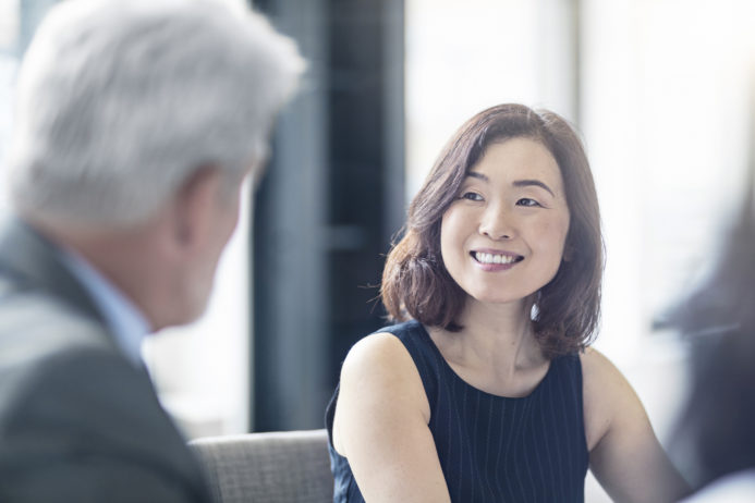 Smiling businesswoman looking at mature coworker
